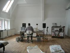 a man is standing in an empty room surrounded by musical equipment and other items on the floor