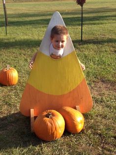 a little boy sitting on top of a fake banana boat with pumpkins around it