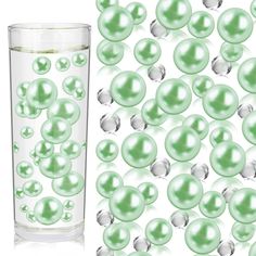 a glass filled with lots of green pearls next to a tall glass full of water