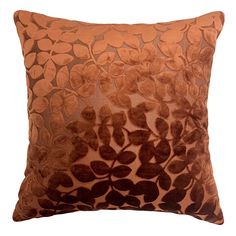 an orange and brown decorative pillow with leaves on the front, sitting on a white background