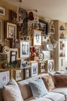 a living room filled with lots of pictures and framed objects on the wall next to a couch