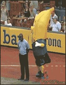 a man holding a banana up to his head while standing on a tennis court in front of a crowd