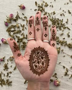 a hand with henna on it next to some dried flowers and petals in the background