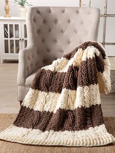 a brown and white blanket sitting on top of a chair next to a gray chair