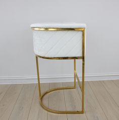 a white and gold side table on wooden floor