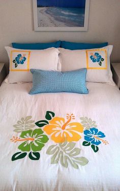 a white bed with blue and yellow flowers on it's comforter in a bedroom