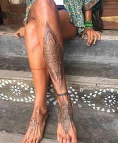 a woman sitting on the steps with tattoos on her legs