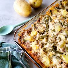 a casserole dish with potatoes and green beans next to it on a table