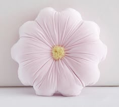 a pink flower pillow sitting on top of a white table