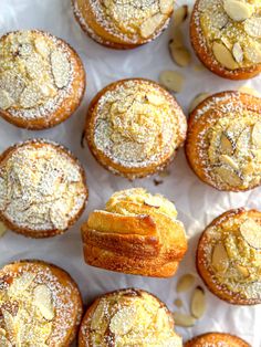 there are many muffins with powdered sugar on them and almonds in the background