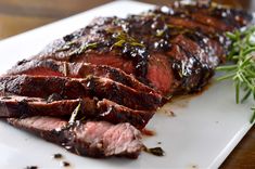 sliced steak on a white plate with herbs