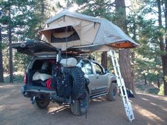 the truck is parked in the woods with its roof tent on