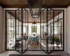 an open glass door leading to a dining room with a blue tablecloth on it