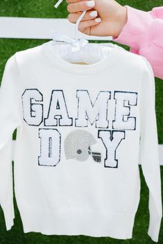 Little ones will love showing their team spirit with our Mini Kids Game Day White Sweater. Made of soft knit material, this sweater features a small white varsity "Game Day" letter and a shiny silver rhinestone helmet patch. Perfect for keeping warm and stylish during games or everyday wear. Go team! All orders are currently shipping within 14 business days. To receive item quicker, expedited shipping is available at checkout. White Long Sleeve Sweatshirt With School Spirit, Collegiate Long Sleeve Sweater For Game Day, Winter Sweater With Ribbed Cuffs For Sports, Winter Sweater With Ribbed Cuffs, Collegiate Sweater For Game Day, White Long Sleeve Sweater For College, White Long Sleeve College Sweater, White Tops With Team Spirit For Fall, Sporty Sweater For Game Day, Fall