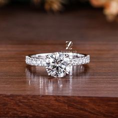 a diamond engagement ring sitting on top of a wooden table