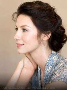 a woman with her hand on her chin looking off to the side, wearing a floral shirt