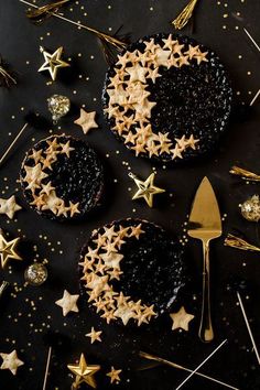 two tarts decorated with gold stars on top of a black surface next to forks