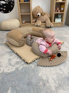 a baby is laying on the floor next to some stuffed animals