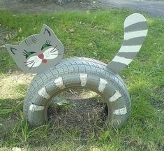 a cat made out of an old tire sitting in the grass