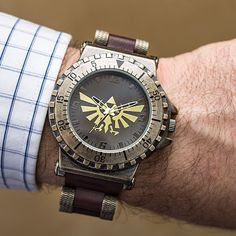 a man wearing a watch on his wrist with the legend of zelda logo on it