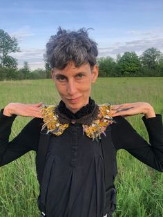 a woman standing in a field with her hands on her hips wearing a black top