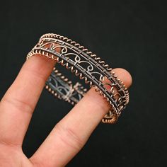 a hand holding a metal ring with filigrees on it's sides