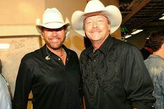 two men standing next to each other wearing cowboy hats