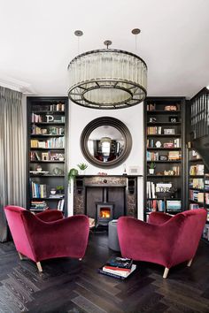 a living room filled with furniture and a fire place under a chandelier hanging from the ceiling