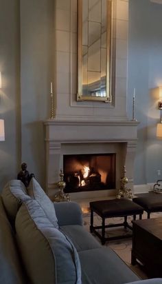 a living room filled with furniture and a fire place in front of a mirror on the wall