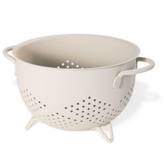 a white colander with handles and holes on the side, sitting on a white surface