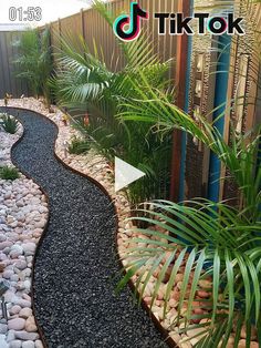 a garden with rocks and plants next to a fence