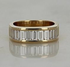 a gold ring with baguets and diamonds on the side, sitting on a white surface