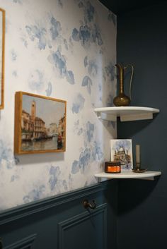 shelves with pictures and vases on them in a room that has blue wallpaper