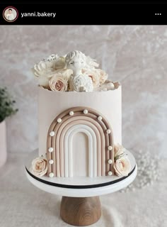 there is a white cake with flowers on the top and an arch in the middle