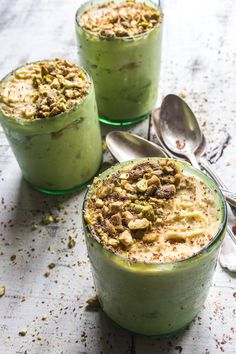 three desserts in glass bowls with spoons next to them