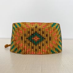 Beaded Bracelet made by Women Artisans from the Inga indigenous community in Putumayo, Colombia. The Inti bracelet has the design of the sun, which is the symbol of the creator. Sibundoy Valley, home of the Inga, is called the valley of the sun. ⁣Inti is the word for sun in their language. - Material: seed bead - Size: 1.5 inches wide, the bracelet is adjustable to many wrist sizes. Check out the matching Plumas and Plumitas earrings, too! Spiritual Resizable Bracelet For Festivals, Resizable Beaded Bangle Bracelet For Festivals, Resizable Beaded Bangle Bracelets For Festival, Brown Bohemian Bracelets For Festivals, Bohemian Resizable Cuff Bracelet As Gift, Bohemian Resizable Bangle Bracelets, Bohemian Resizable Cuff Bracelet For Gift, Bohemian Bracelets For Friendship And Festivals, Bohemian Resizable Cuff Bracelet Gift