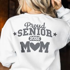 a woman wearing a white sweatshirt with the words proud senior mom printed on her back