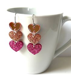 Love these light pink heart shape sparkle confetti resin dangle earrings!  You will get so many compliments when you wear these! The earrings are made with clear resin and large sparkly multi color glitter. The top heart has a pink mirror effect. These fun dangle earrings are lightweight and sassy! Please take these earrings off when jumping in water.  They are water resistant, but will last longer if kept out of being drenched by water. Pink Glitter Earrings For Valentine's Day, Pink Glitter Heart Earrings For Party, Valentine's Day Pink Glitter Earrings, Pink Glitter Jewelry For Valentine's Day, Valentine's Day Pink Glitter Jewelry, Wood And Resin Jewelry, Light Pink Heart, Clear Mirror, Wood Resin Jewelry