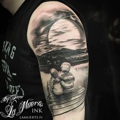 a man's arm with a black and white tattoo on it, depicting two people sitting in a boat