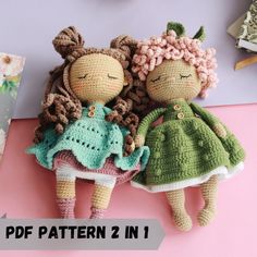 two crocheted dolls sitting next to each other on top of a pink surface