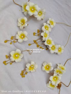 four white and yellow flowers are on a table with brown string attached to the headbands