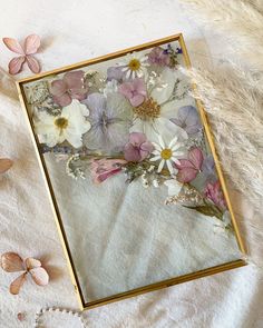 an image of flowers in a frame on a bed with pearls and beads next to it