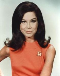 an old photo of a woman with long black hair and orange dress on her cell phone