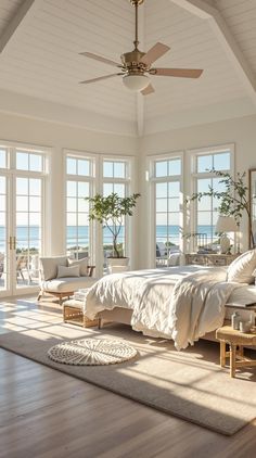 a bedroom with white walls and wood flooring has large windows overlooking the ocean as well as a bed