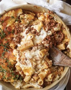 a casserole dish with meat, cheese and sauce in it on a white cloth