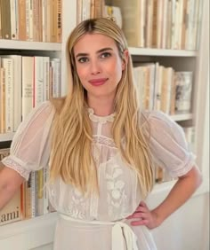 a woman standing in front of a bookshelf with her hands on her hips