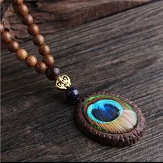 This Exquisite Vintage Wood Pendant Necklace Features A Mesmerizing Blue-Green Peacock Feather Design, Carefully Encased In A Round Wooden Frame. The Pendant Is Suspended From A Sturdy Brown Wooden Beaded Chain, Adding A Touch Of Elegance To This Unique Piece. The Necklace Is Not Only A Fashionable Accessory But Also A Meaningful Symbol Of Beauty And Renewal, Making It A Perfect Gift For Yourself Or Someone Special. Vintage Wood Pendant Necklace Blue-Green Peacock Feather Design Wooden Beaded Chain Elegant And Meaningful Accessory Perfect Gift For Any Occasion Wooden Peacock, Peacock Feather Pendant, Heishi Jewelry, Peacock Feather Design, Green Peacock, Peacock Green, Feather Pendant, Feather Design, Wood Pendant