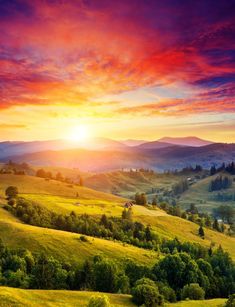 the sun is setting over a lush green valley with rolling hills and trees in the distance