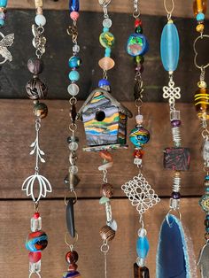 a birdhouse hanging from the side of a wooden wall filled with lots of different colored beads