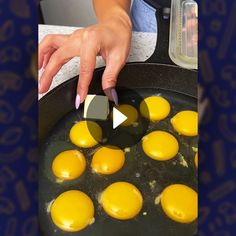 a woman is frying eggs in a skillet on the stove with her fingers